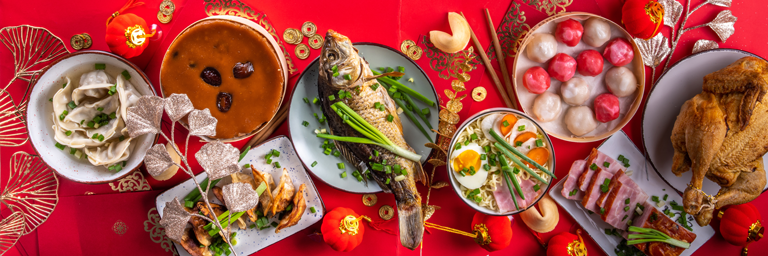 Tafel asiatischer Festgerichte zum Neujahr vor rotem Hintergrund