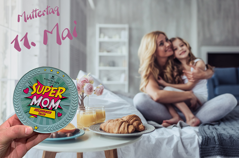 Mutter mit Tochter im Bett und im Fokus liegt ein Frühstück am Bett