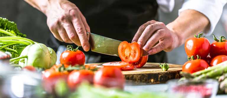 Mann steht in der Küche und schneidet Tomaten