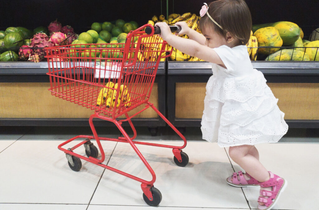 Kind schiebt kleinen Einkaufswagen
